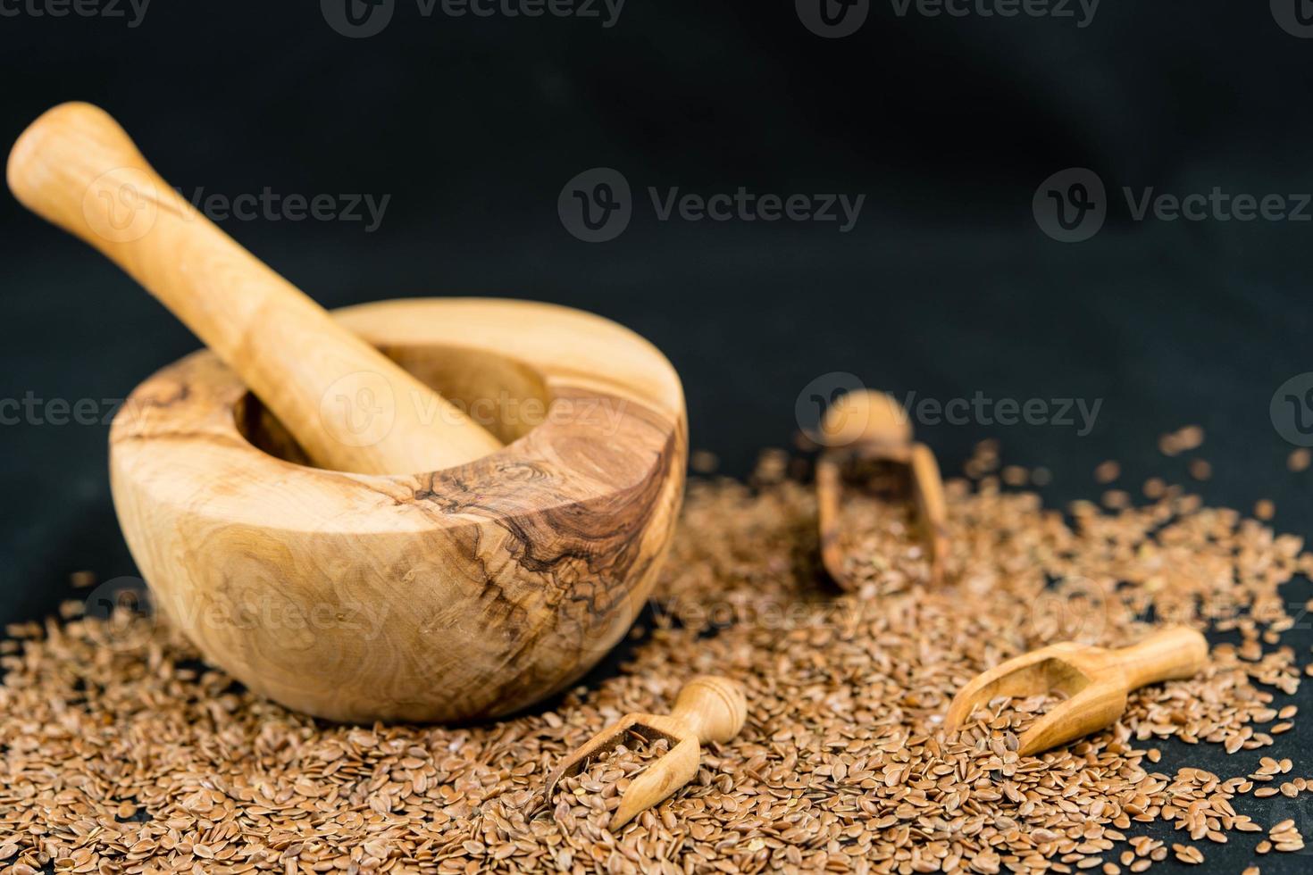 a pile of flaxseeds and utensils made of olive wood photo