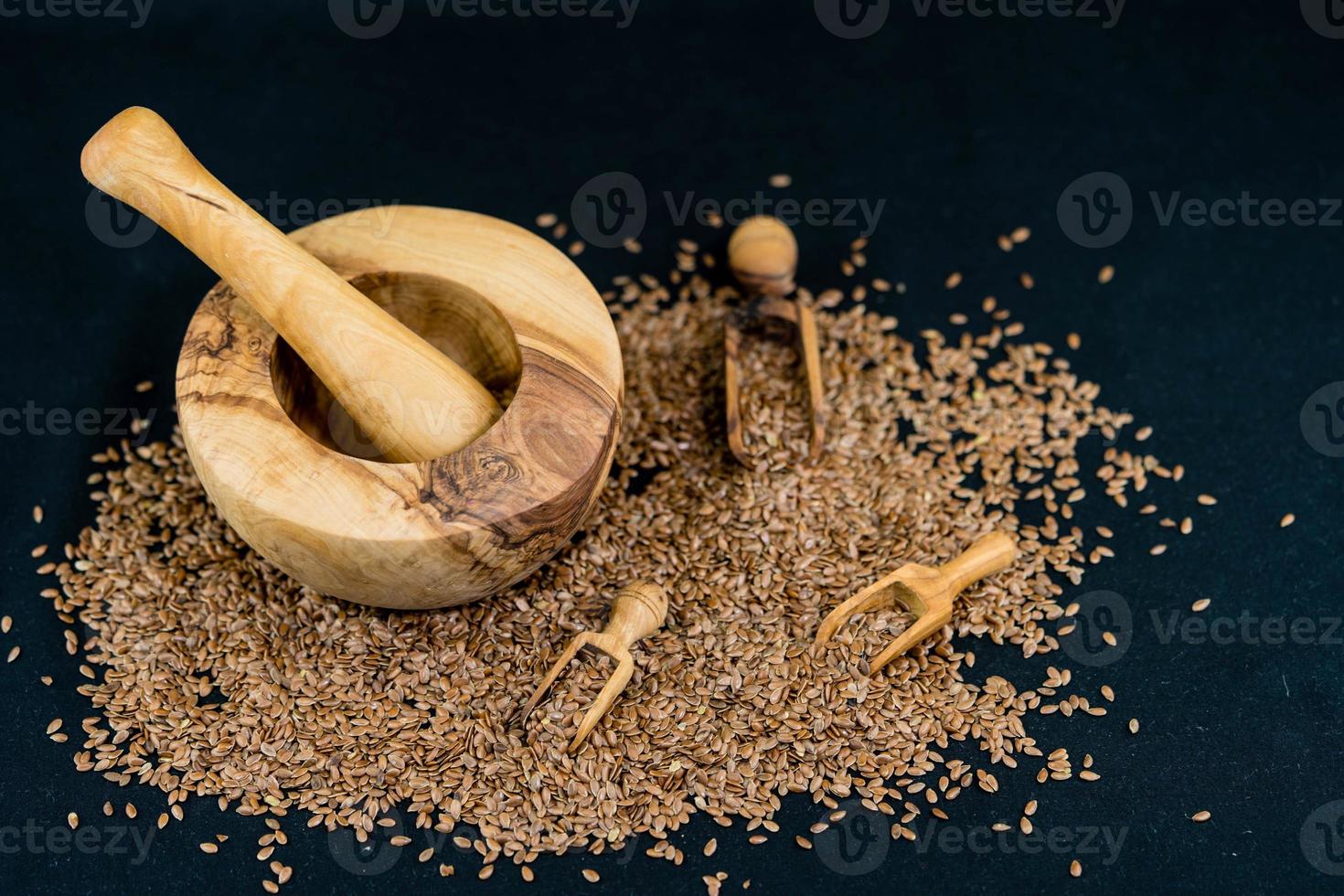 a pile of flaxseeds and utensils made of olive wood photo
