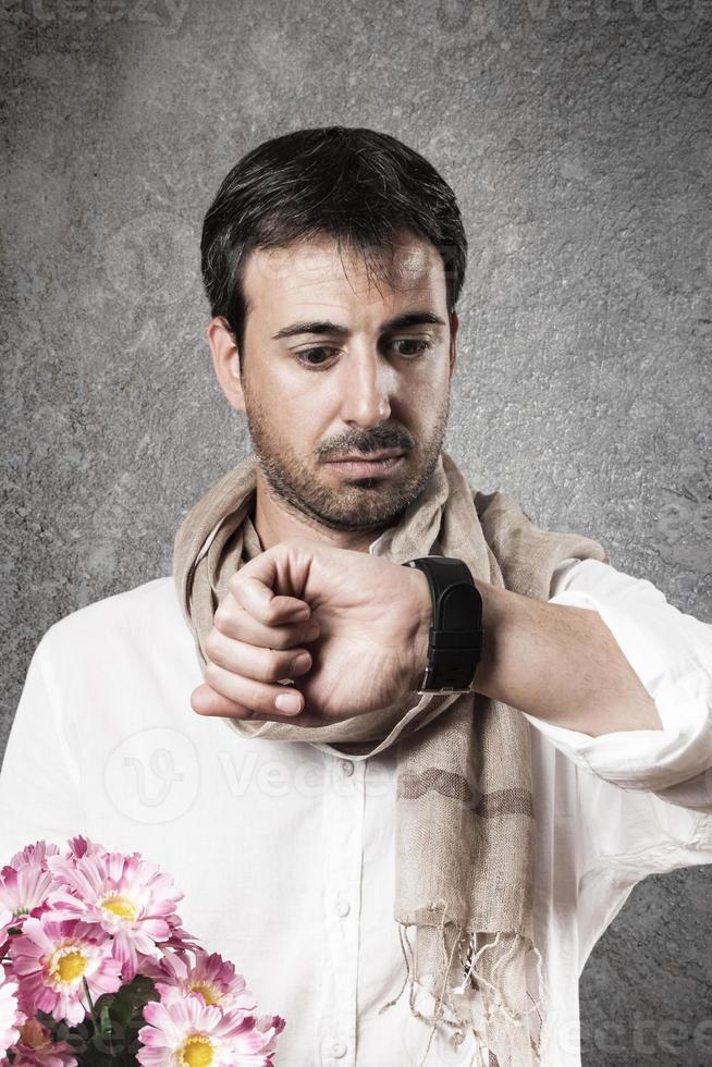 hombre enamorado de un ramo de flores mirando el reloj con preocupación. imagen vertical foto