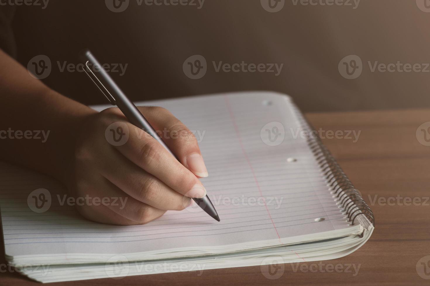 un hombre escribiendo con un bolígrafo en el diario de un cuaderno en el concepto de oficina de negocios y educación, entra la luz del sol, cierra. foto