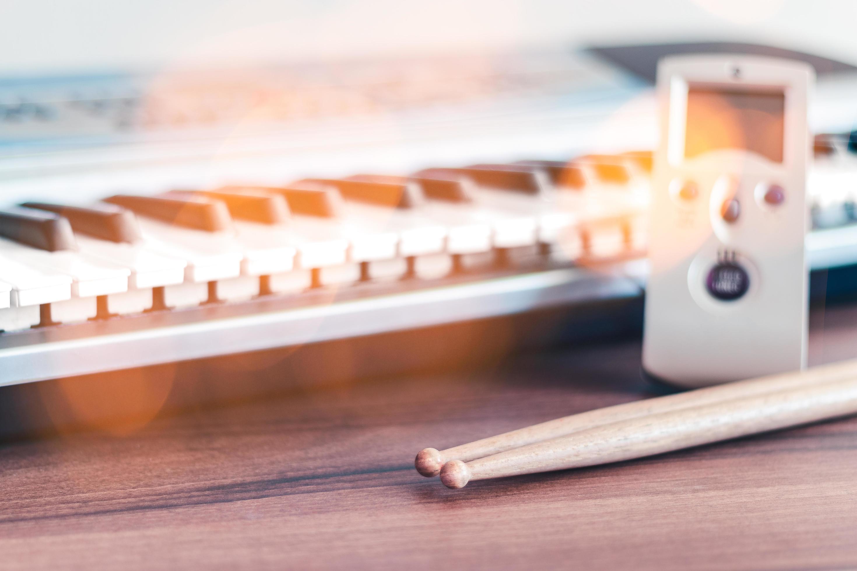 Drum sticks, electric keyboards and metronome as a backdrop, ready for