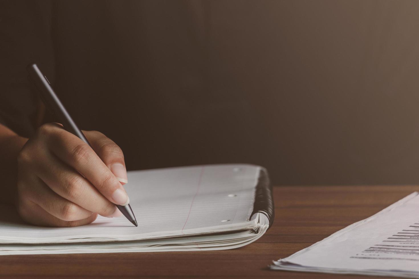 Man writing with a pen in Notebook diary In the concept of business office and education , there is sunlight coming in, Close up. photo