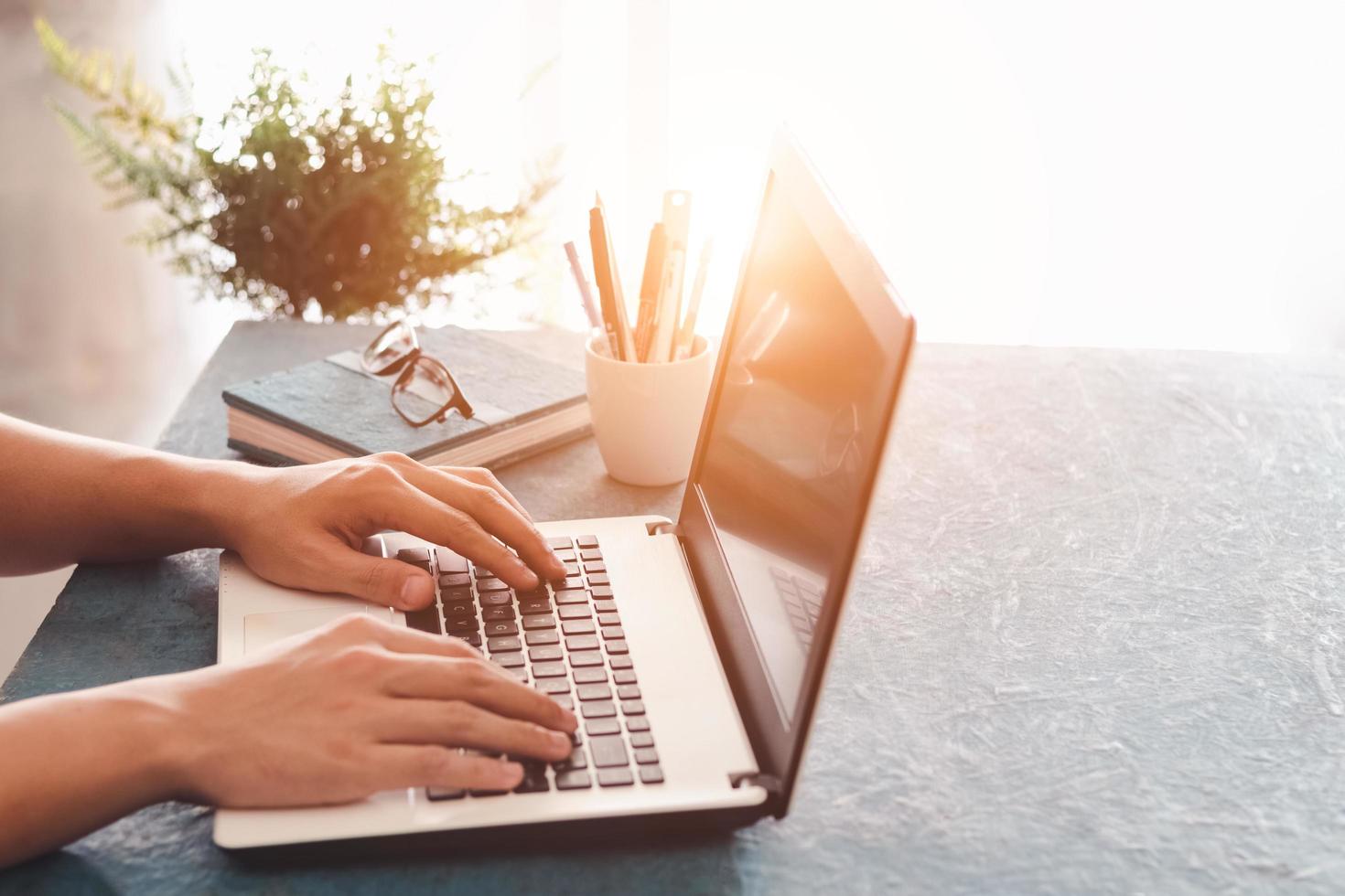 Close up shot of male hands typing on laptop while sitting at office desk indoors, man fingers tapping and texting on computer keyboard while working in cabinet, Work concept. photo