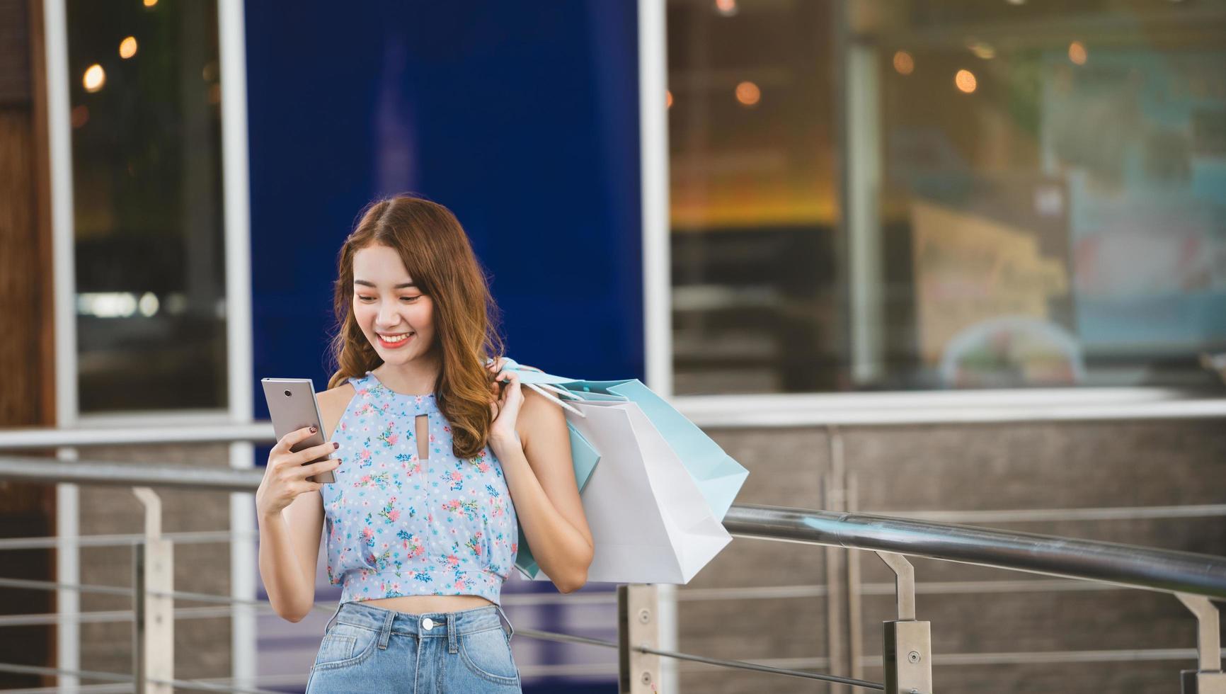 una joven asiática usa un teléfono móvil cuando va de compras foto