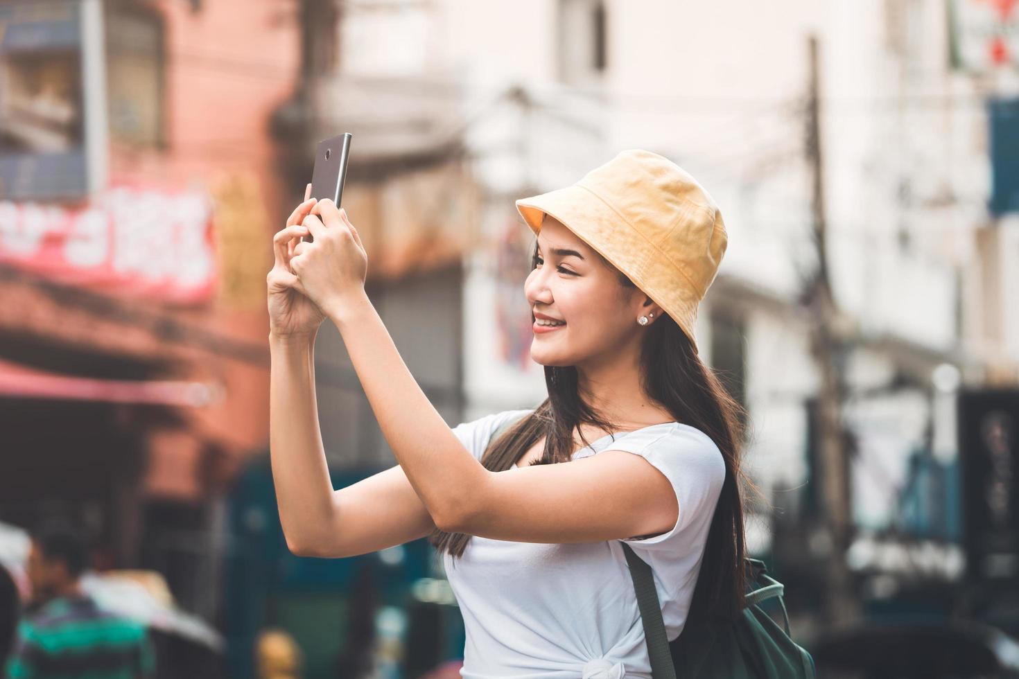 mujer asiática joven que viaja en bangkok. usando un teléfono inteligente tomar una foto. foto