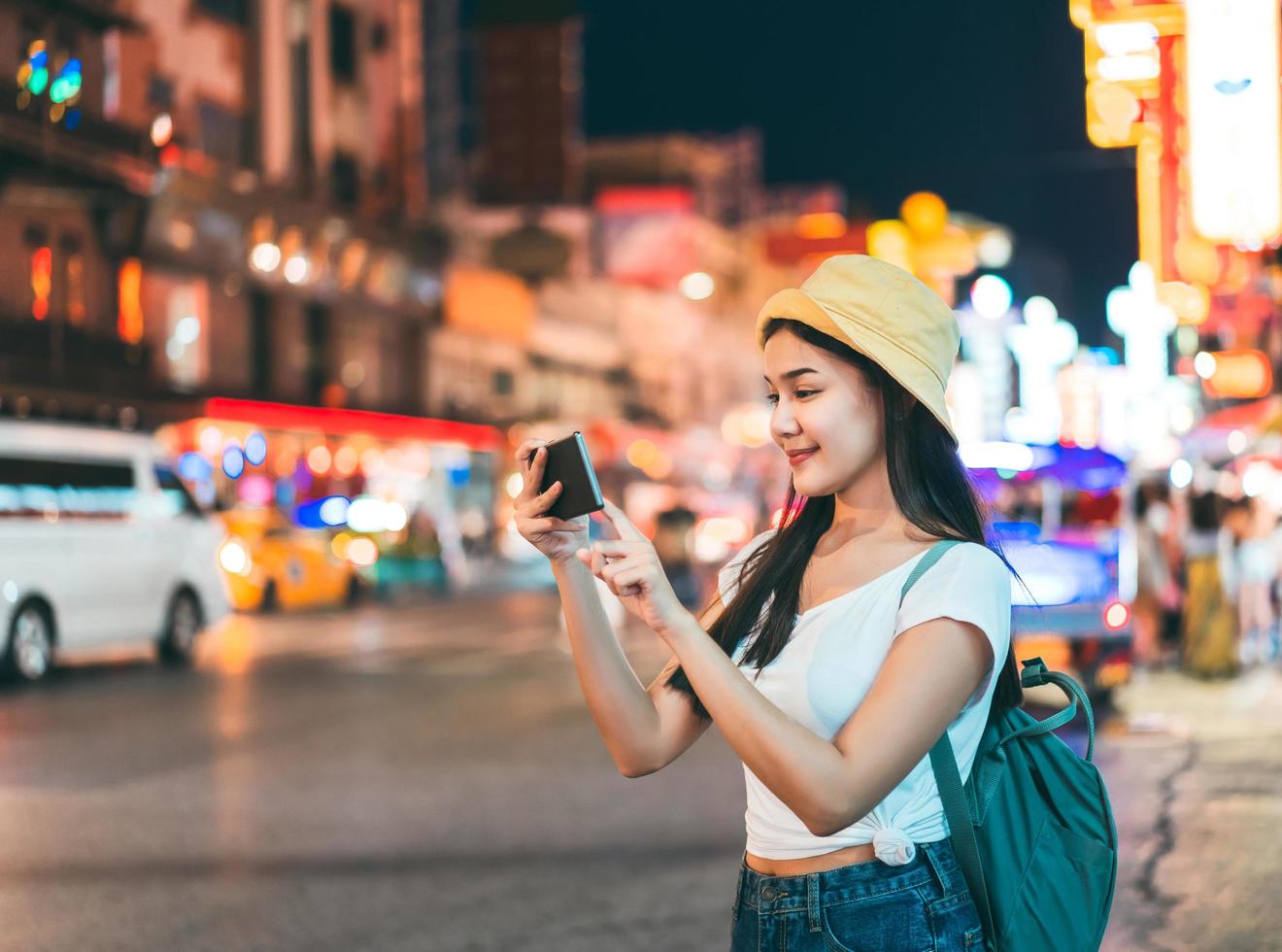 mujer asiática joven con teléfono inteligente. fondo de la carretera Khaosan. foto