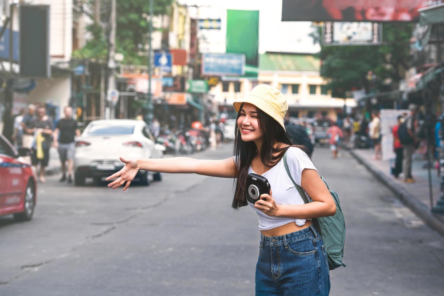 Asian womanflag down a taxi in bangkok with instant camera photo