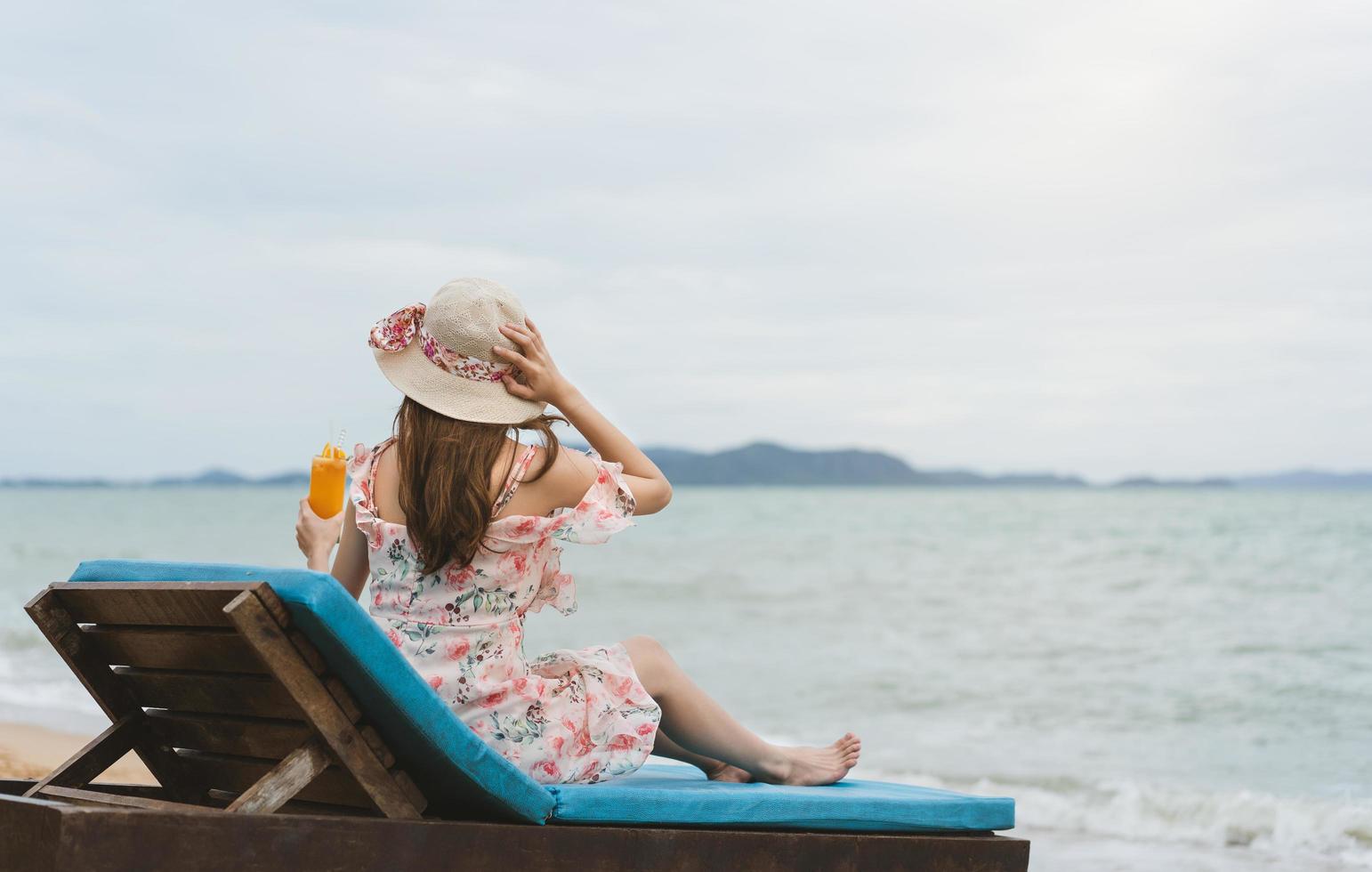 Relájese joven con sombrero bebiendo refrescante cóctel de naranja foto