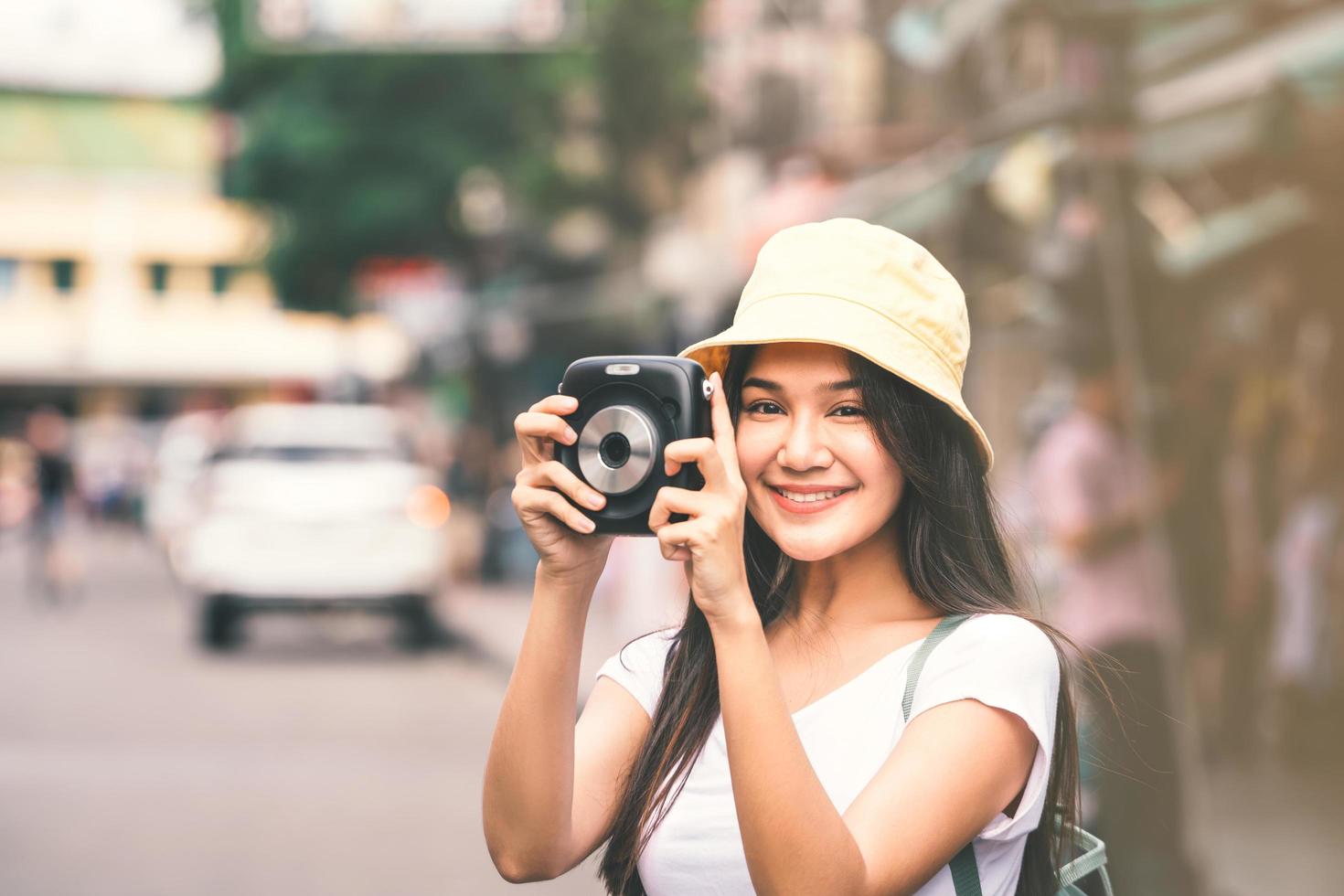 mujer viajera asiática con cámara instantánea en khaosan foto