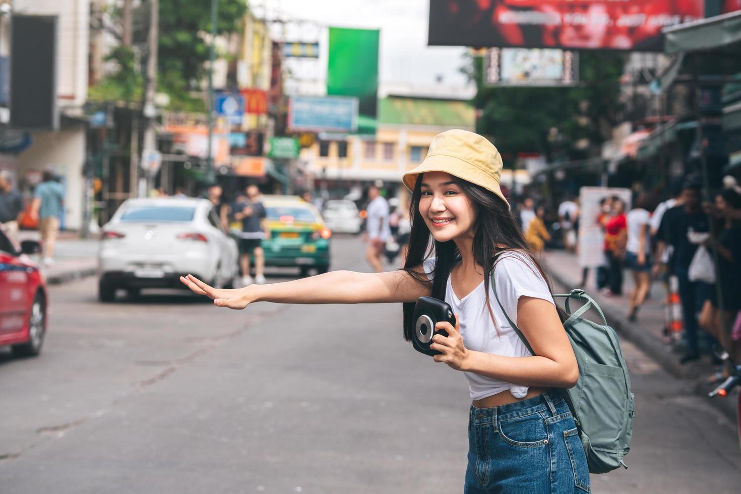 Young asian woman hold instant film camera and call taxi in Bangkok, Thailand. photo