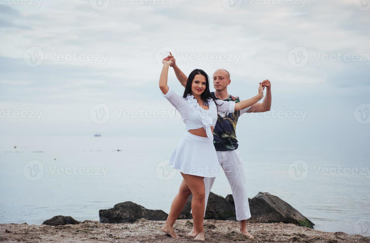 Beautiful inflammatory couple dancing on the beach photo