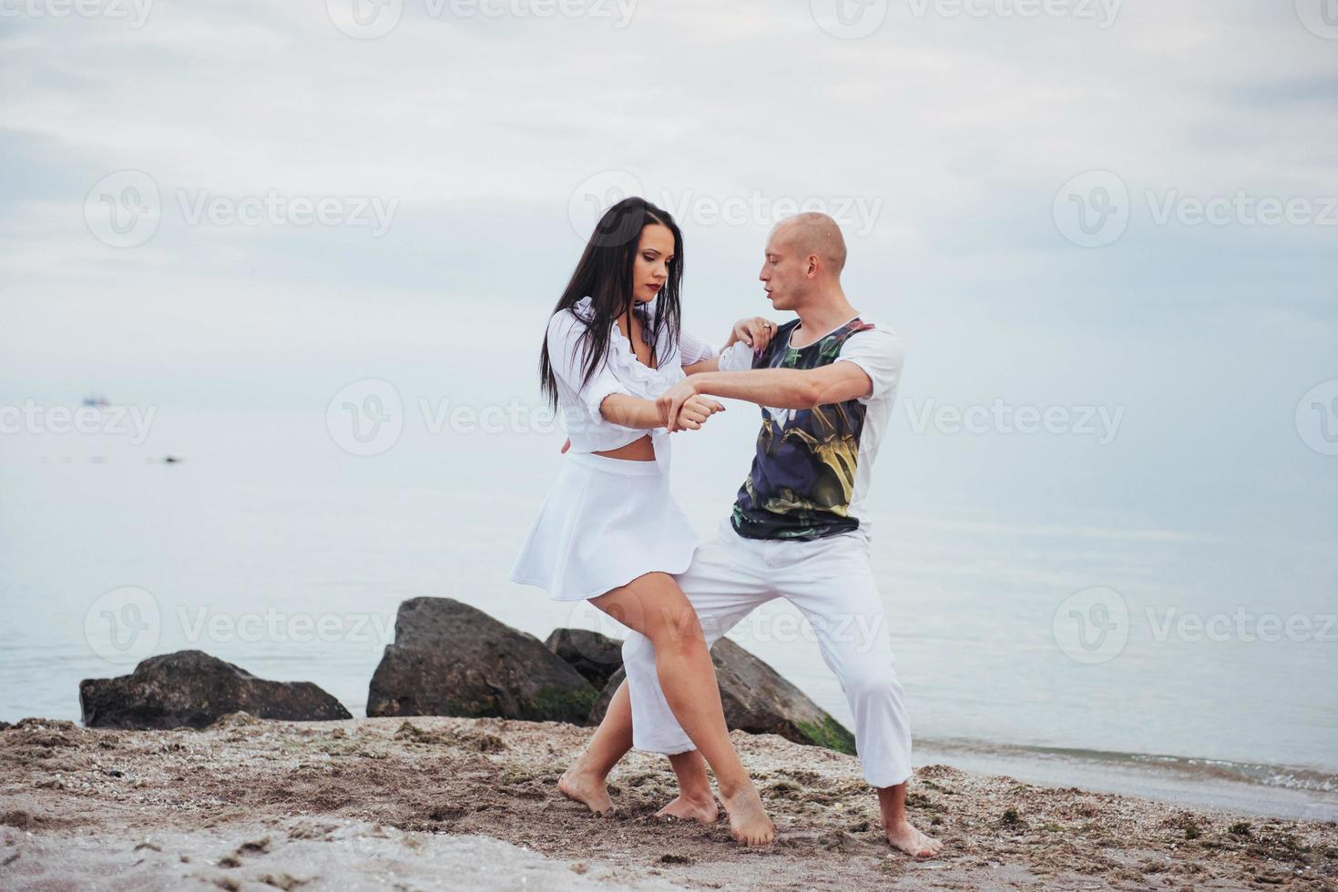 beautiful couple dancing on the beach at the background photo