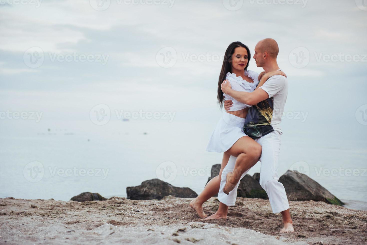 beautiful couple dancing on the beach at the background photo