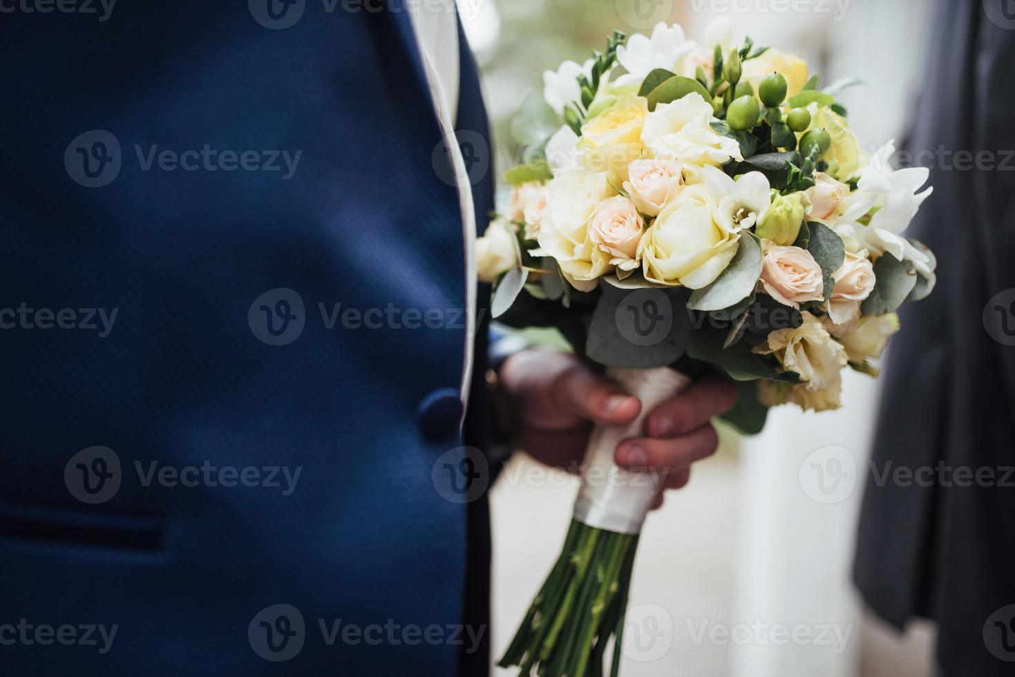 wedding bouquet in hands of the groom photo