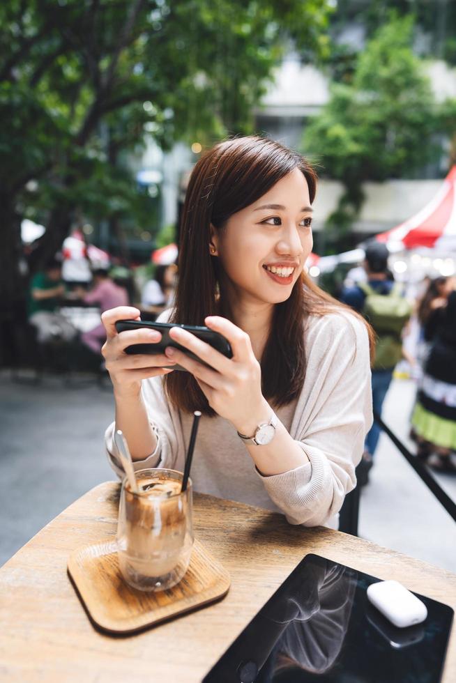 Relax asian woman at cafe using smart phone for social media. photo