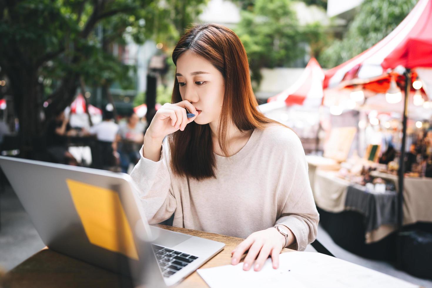 Business freelancer adult asian woman using laptop computer for work at sidewalk cafe photo