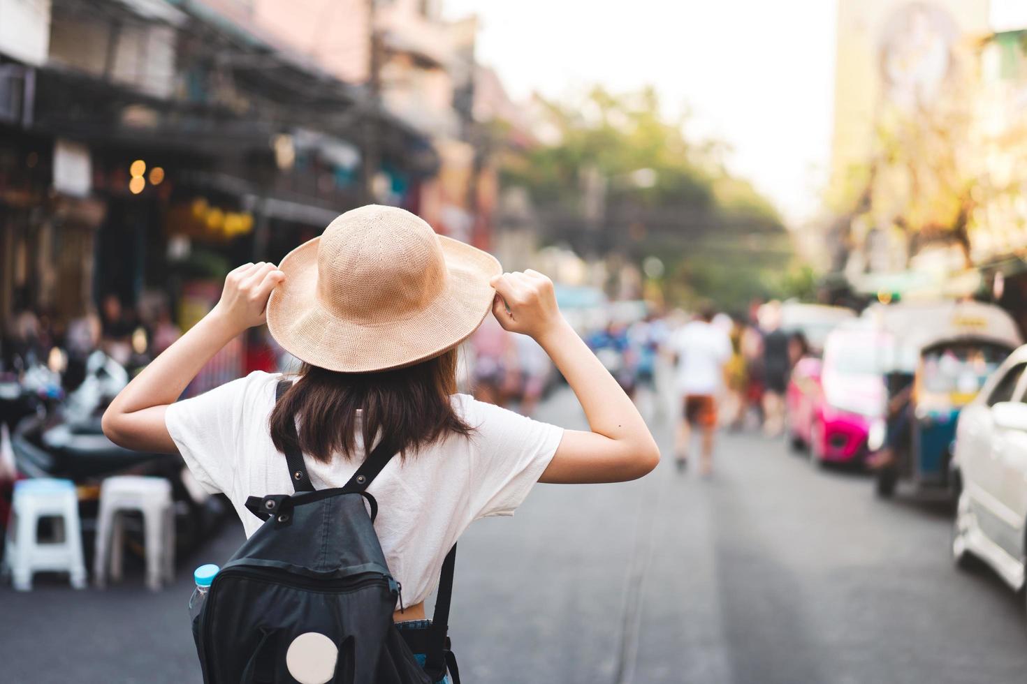 vista posterior de la mochila de viaje de una joven asiática en el mercado callejero. foto