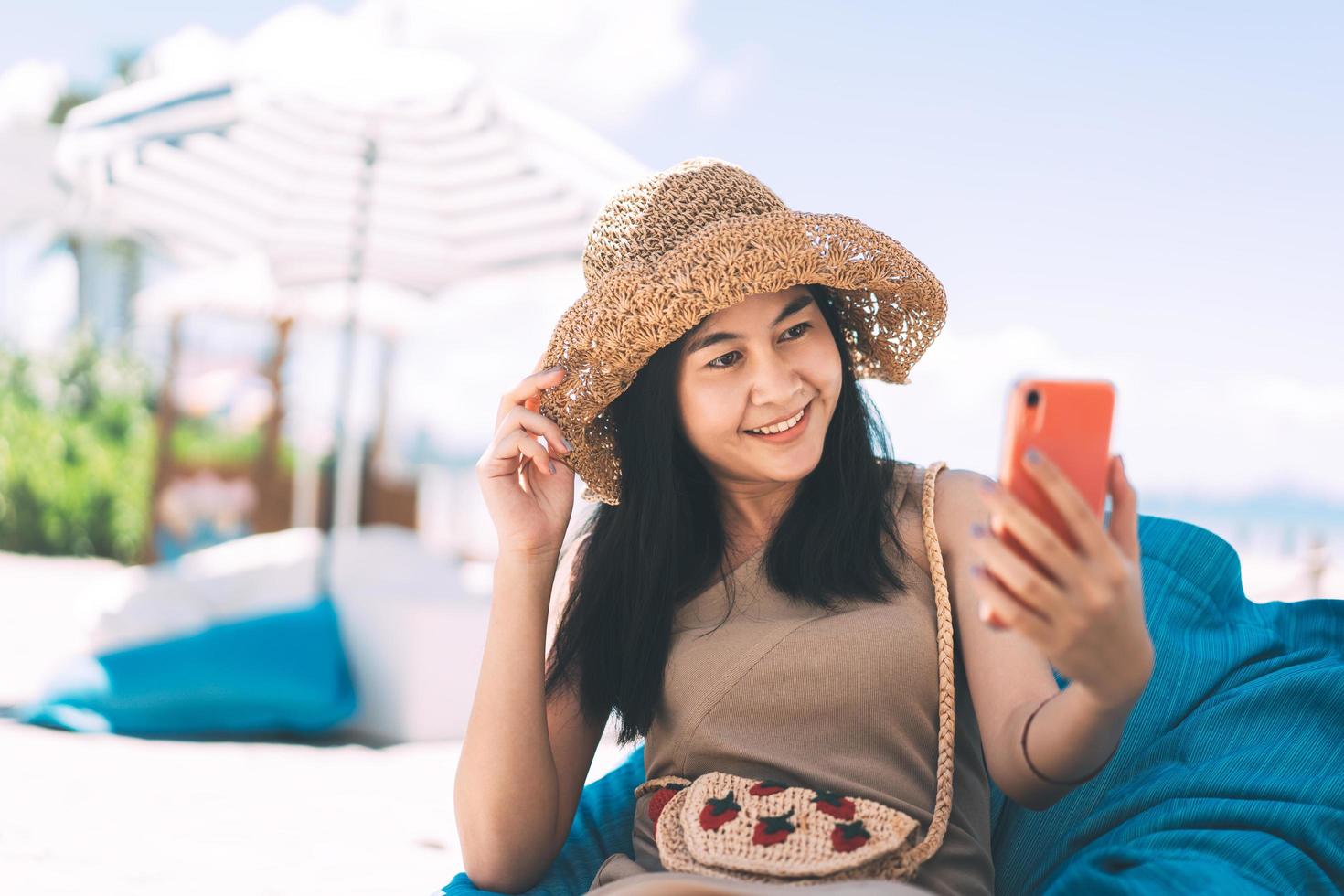 Travel asian woman relax at beach cafe and using mobile phone for video call via online internet. photo