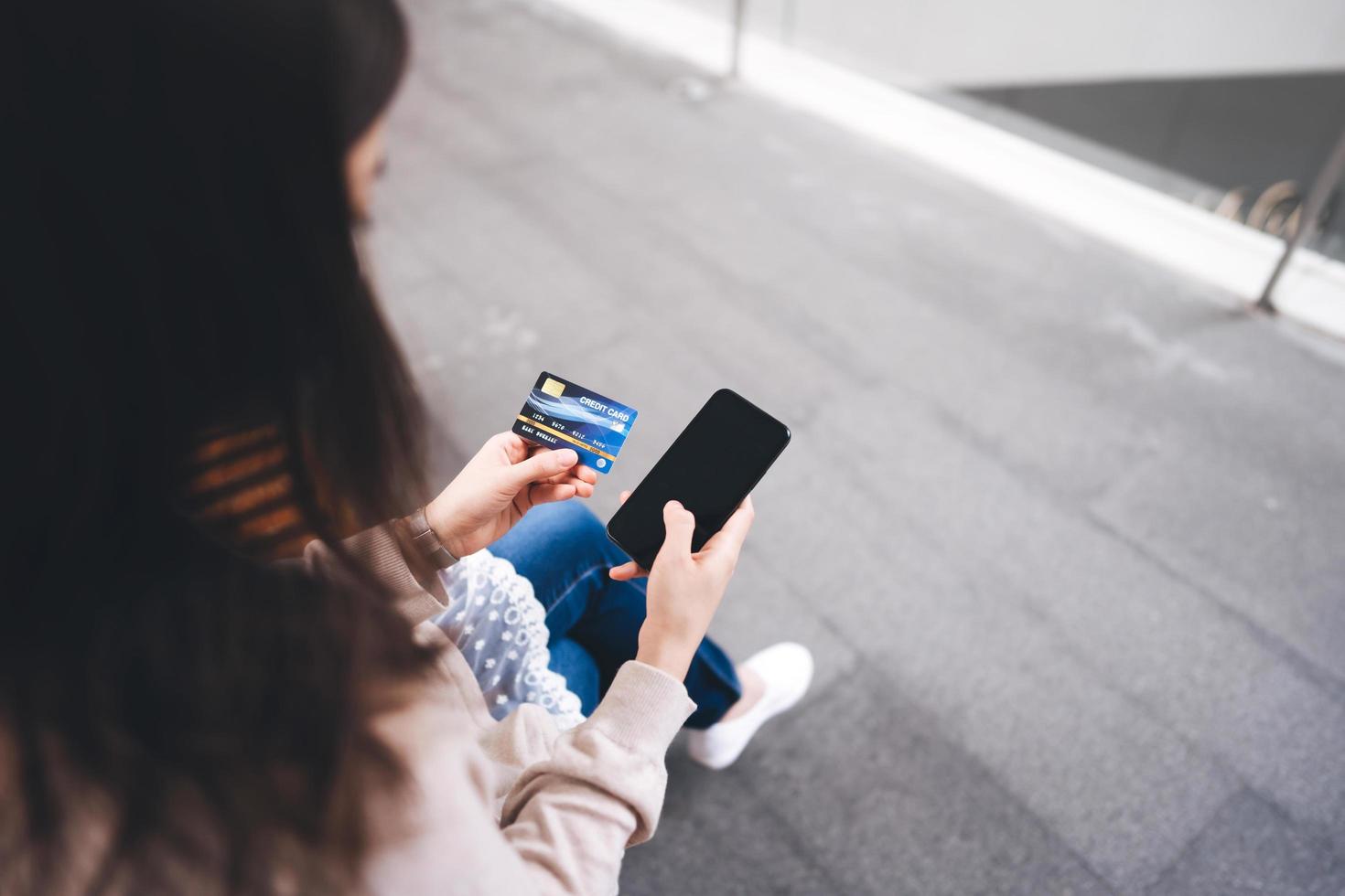 Rear view of  asian woman using smart phone for shopping online payment with app photo