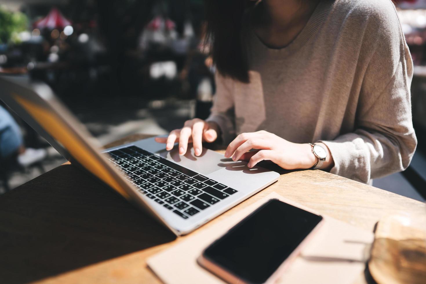 Adult asian woman hand using laptop for work on weekend at outdoor cafe on day photo