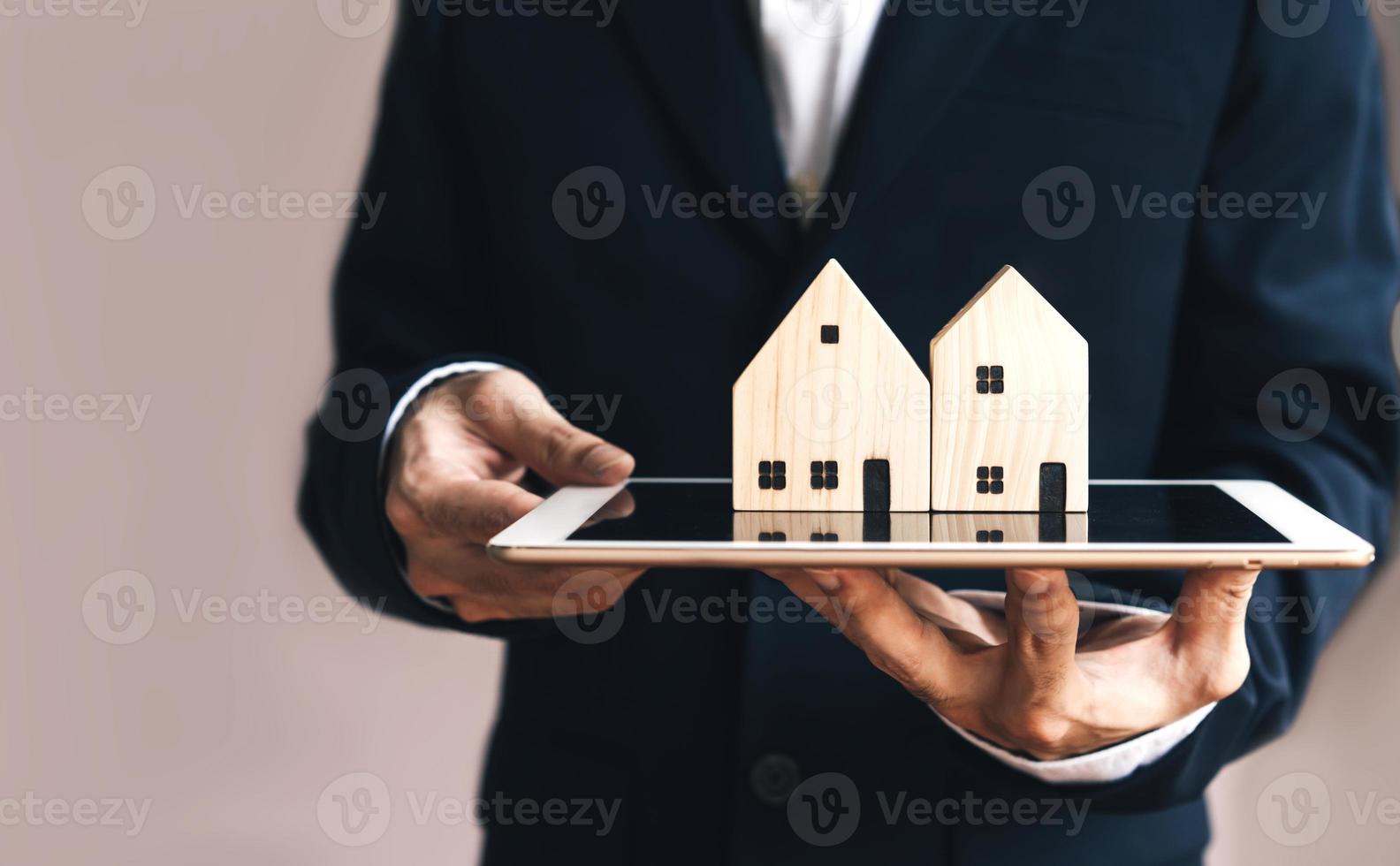 Business realtor man holding digital tablet with home model for online media concept photo