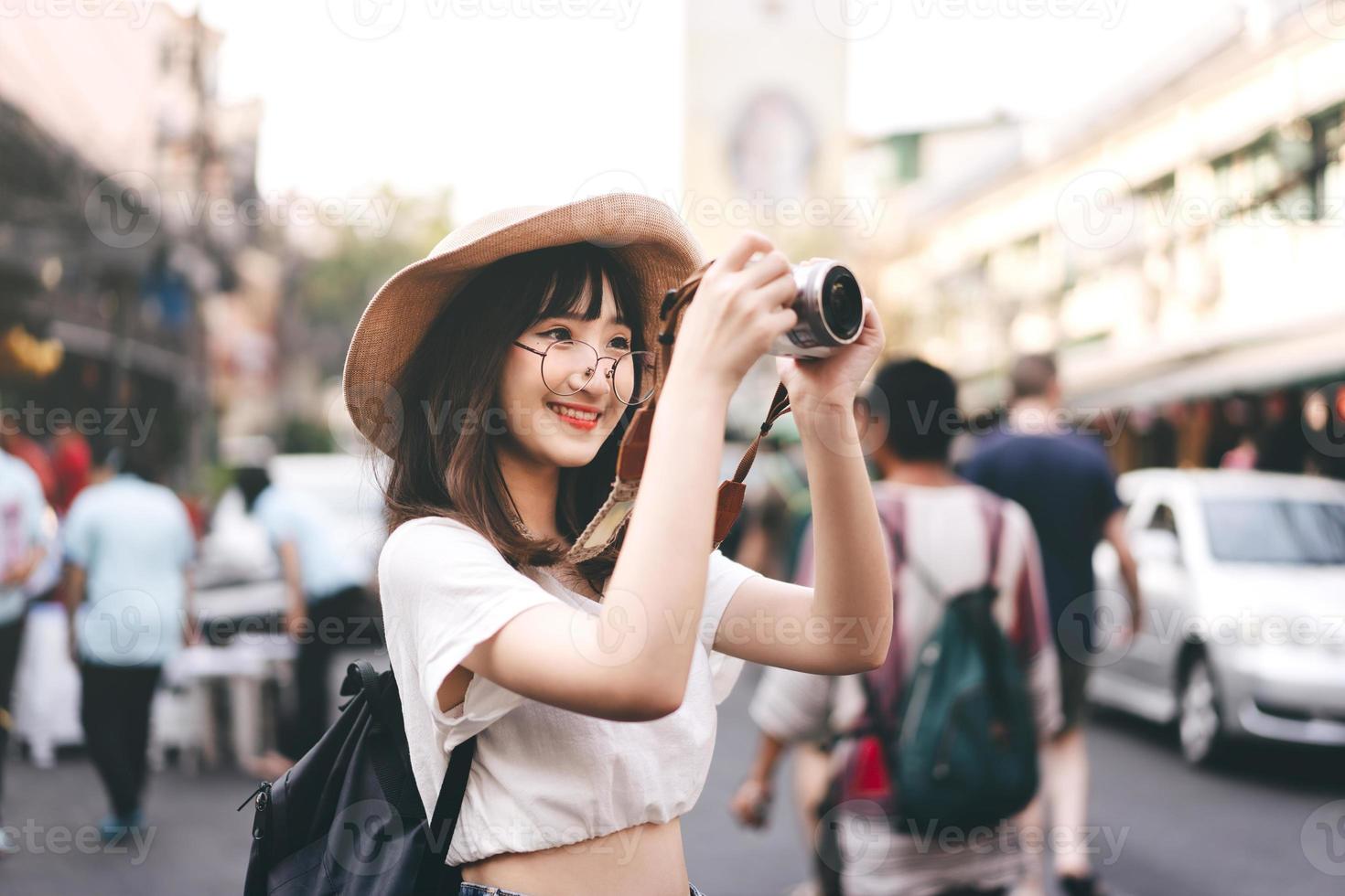 Young asian woman traveller take a photo by camera at khaosan street road.