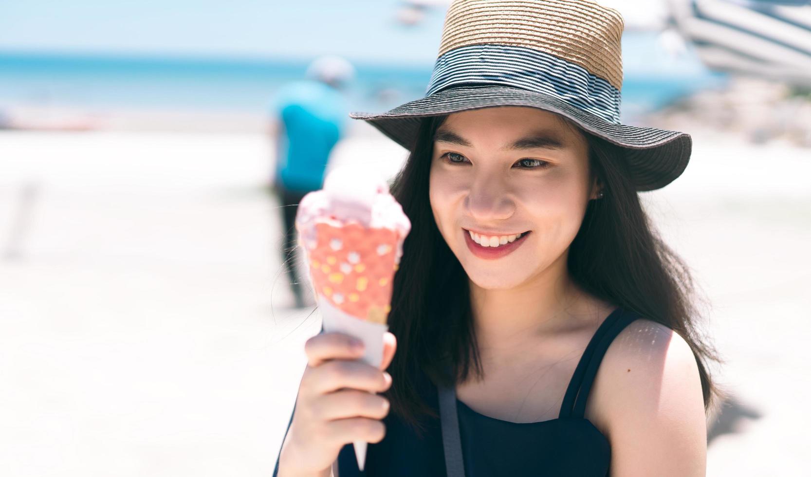 Young adult woman summer travel relax eating ice cream cone at outdoor beach cafe photo