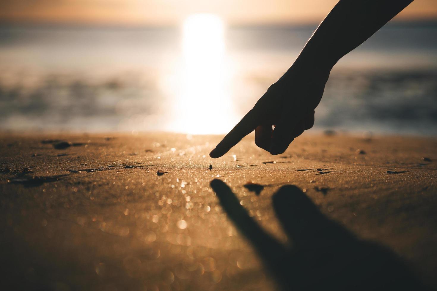 Human hand point to tiny cute crab on the beach sand photo