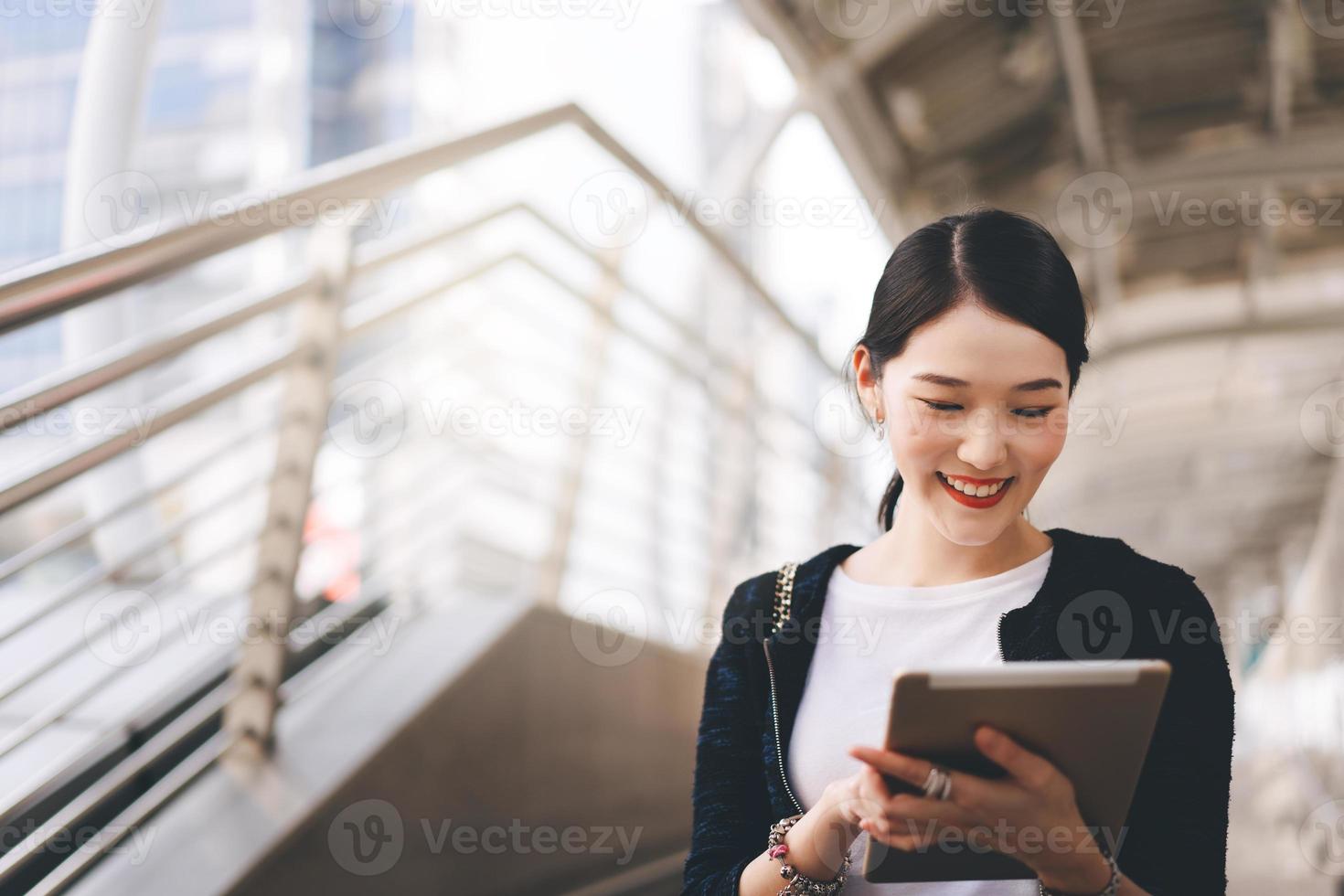 mujer asiática que trabaja en una empresa de adultos jóvenes que usa una tableta digital para la aplicación en línea el día. foto