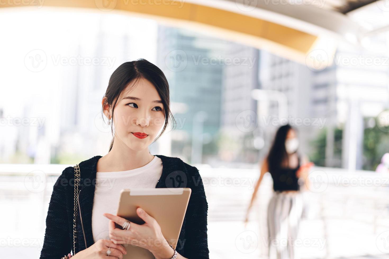 mujer asiática que trabaja en una empresa de adultos jóvenes que usa una tableta digital para la aplicación en línea el día. foto