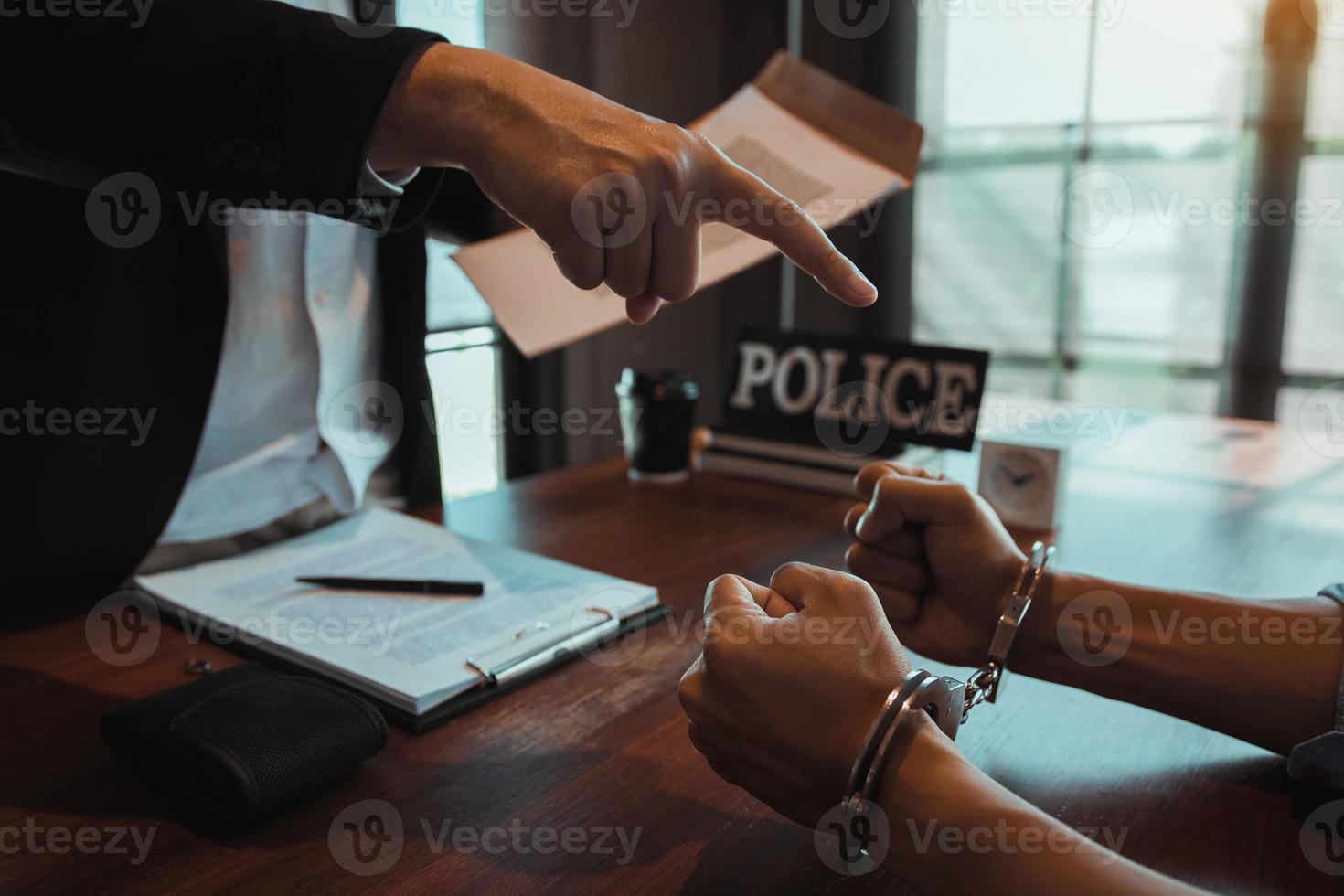 el oficial de policía señaló las esposas y sostuvo los documentos para arrestar al acusado en un caso de fraude. foto