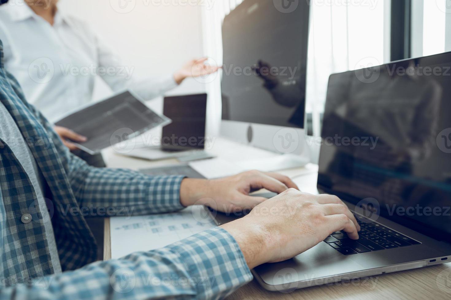 Two partnerships developing programming and coding technologies working on laptop and analyzing together. photo