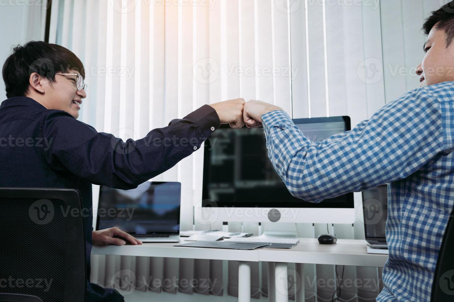 los desarrolladores de software de empleados asiáticos celebran el éxito del proyecto con un golpe de puño en la sala de la oficina. foto