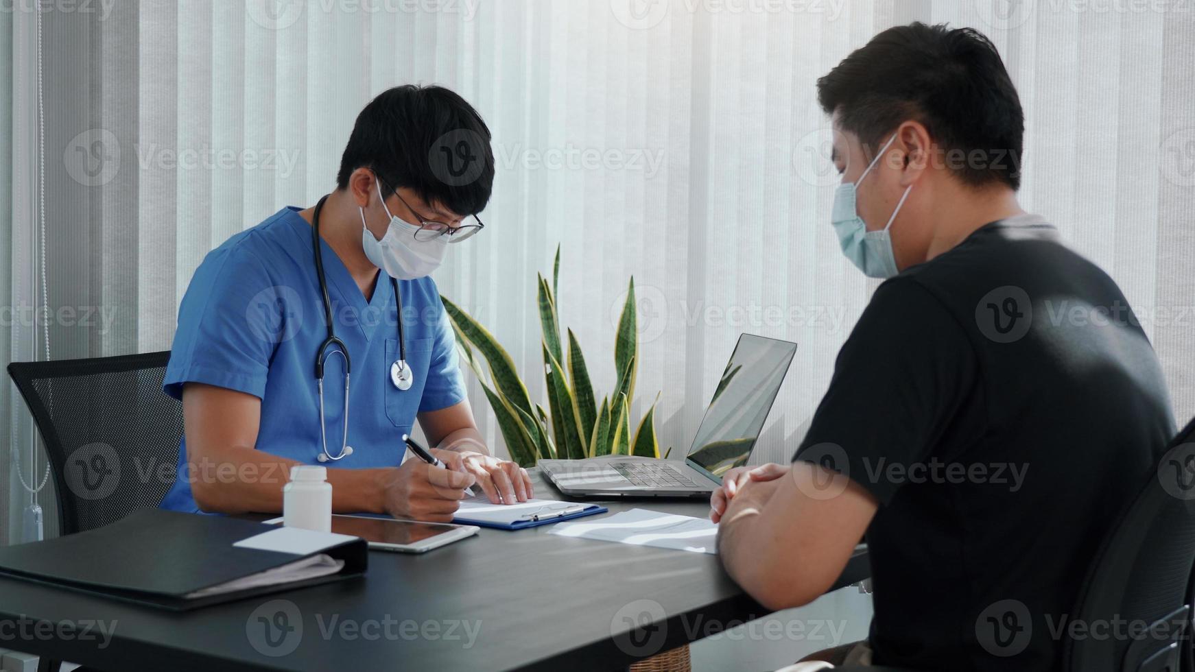 los médicos explican el tratamiento de la enfermedad de un paciente mientras usan una máscara durante la epidemia. foto