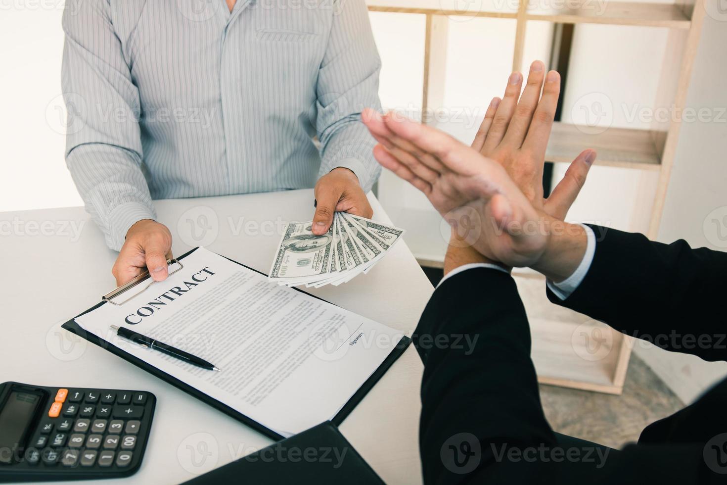 Businessperson refusing bribe given money by partner with anti bribery corruption concept. photo