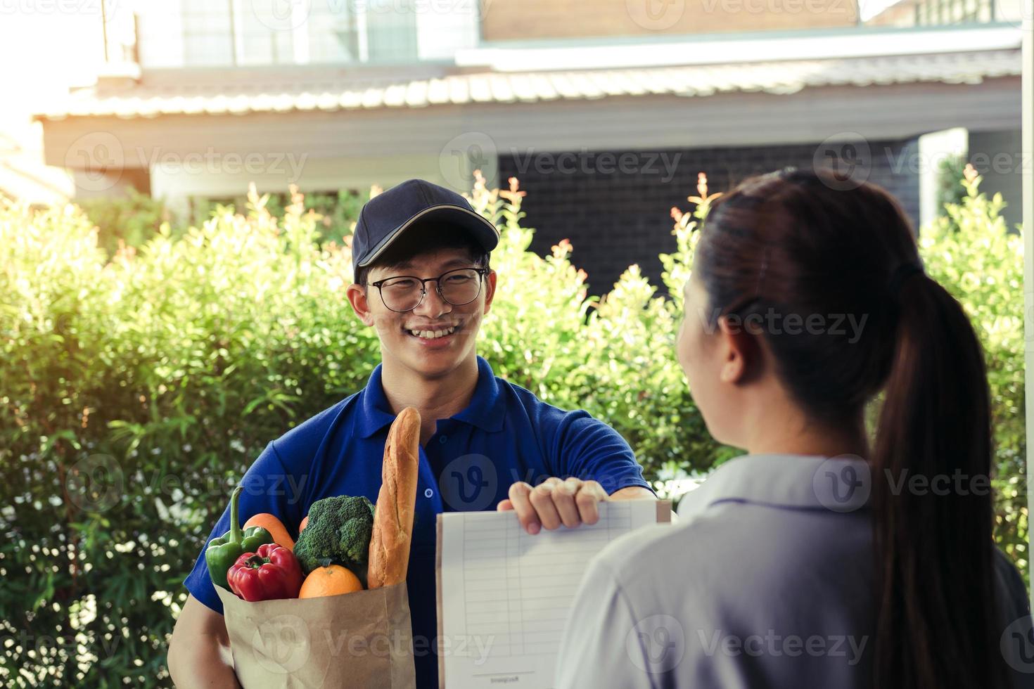 Supermarket food delivery staff deliver bags to female customers in front of the house. photo