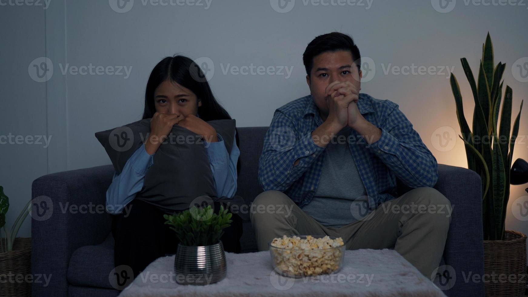 Asian couple in the living room watch a horror movie in the middle of the night. photo