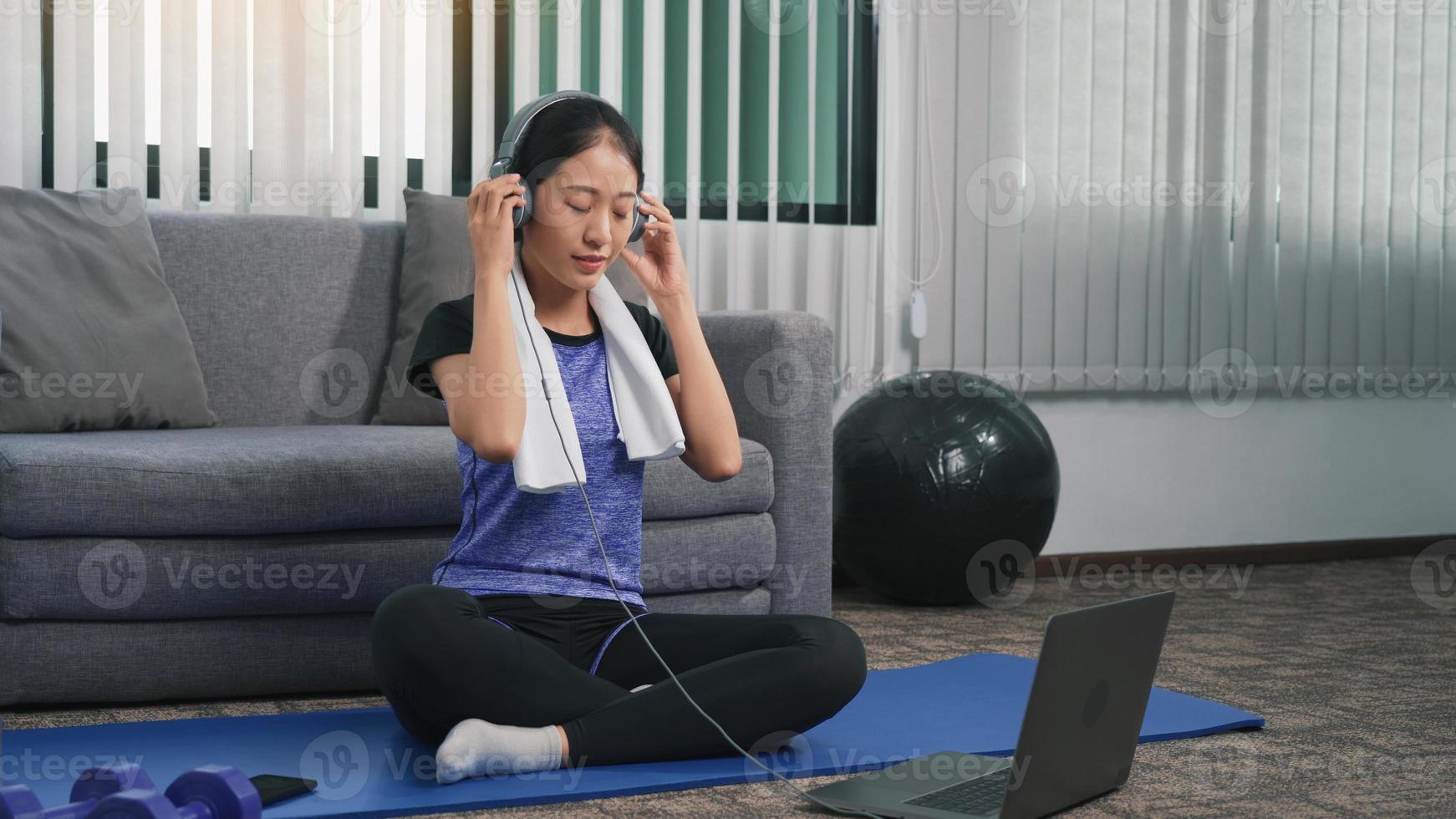 una joven asiática elige escuchar música mientras hace ejercicio en casa. foto