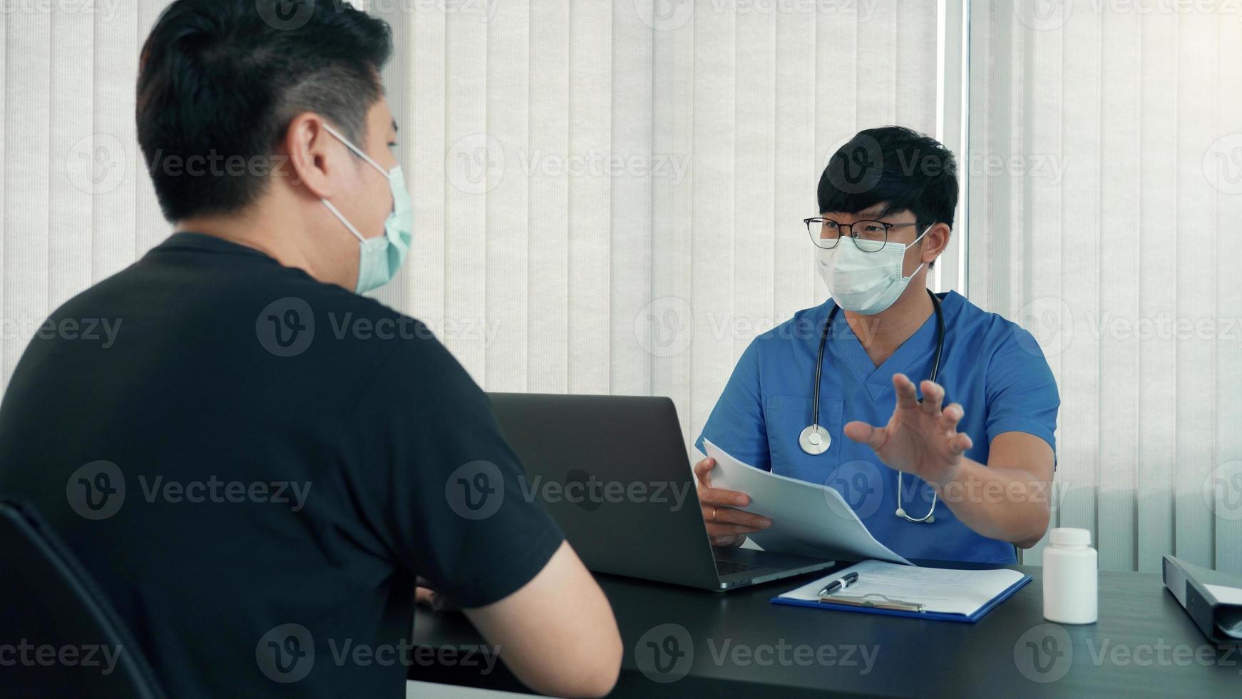 los médicos explican el tratamiento de la enfermedad de un paciente mientras usan una máscara durante la epidemia. foto