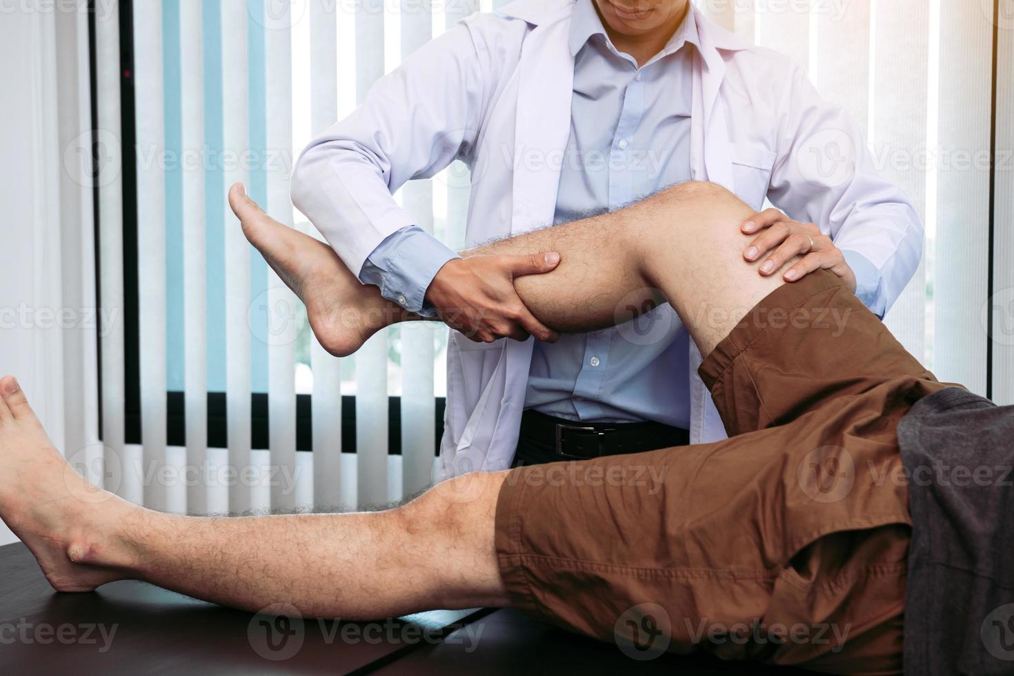 los fisioterapeutas están usando las manos para agarrar el muslo del paciente para comprobar si hay dolor y masaje en la clínica. foto