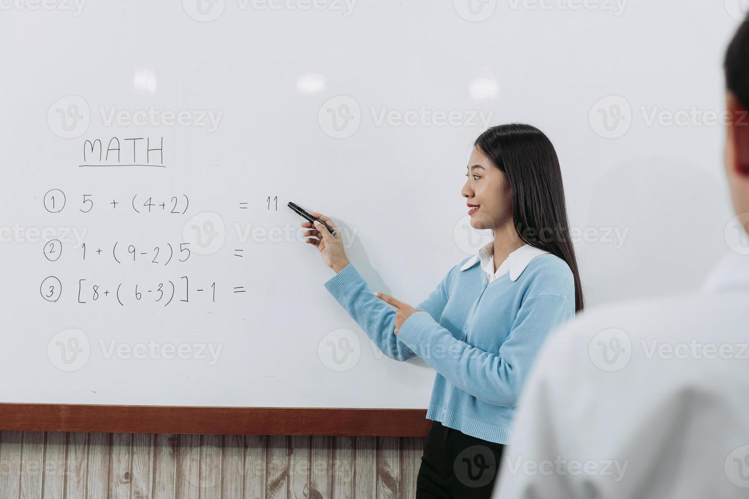 joven profesor asiático enseñando a los estudiantes en el aula. foto