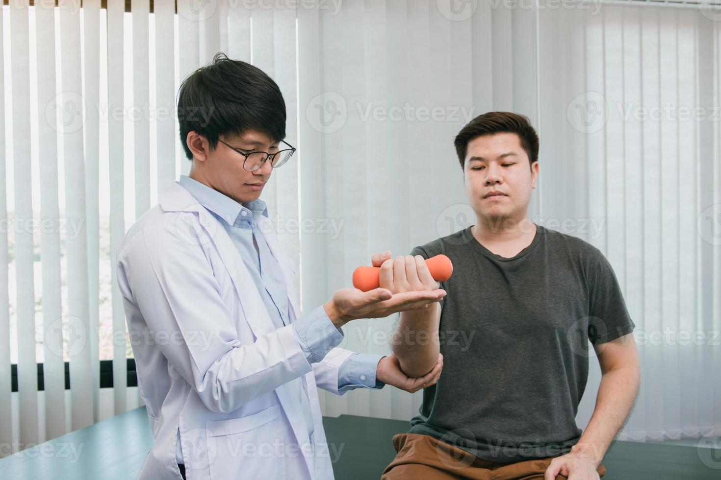 Asian physiotherapists are helping patients lift dumbbells for arm recovery. photo