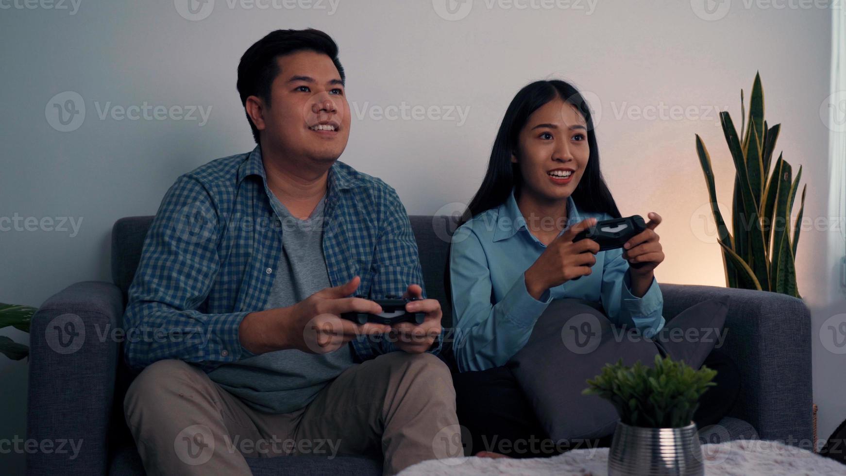 Asian couples are having fun playing games in their living room at night. photo