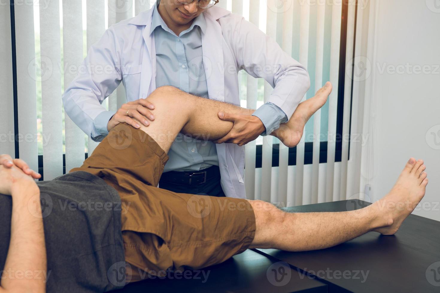 los fisioterapeutas están usando las manos para agarrar el muslo del paciente para comprobar si hay dolor y masaje en la clínica. foto