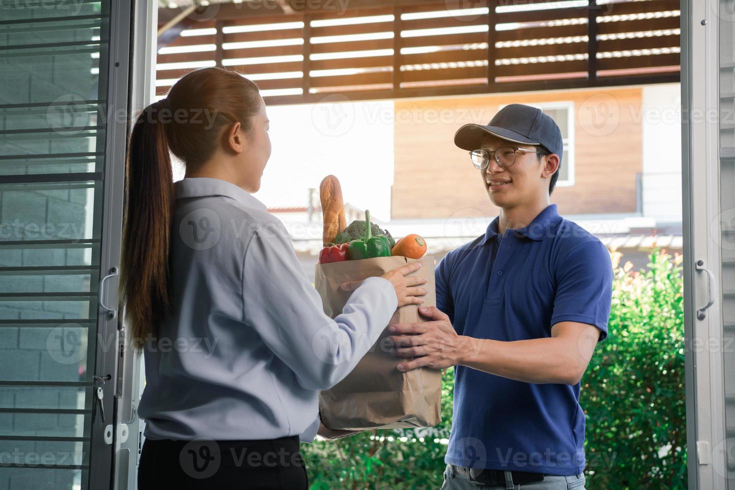 Delivery of an asian man handling a bag of food to a female customer at the door. photo