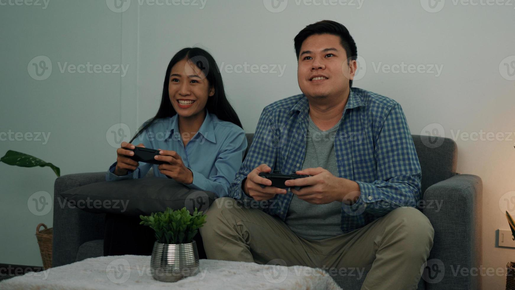 Asian couples are having fun playing games in their living room at night. photo