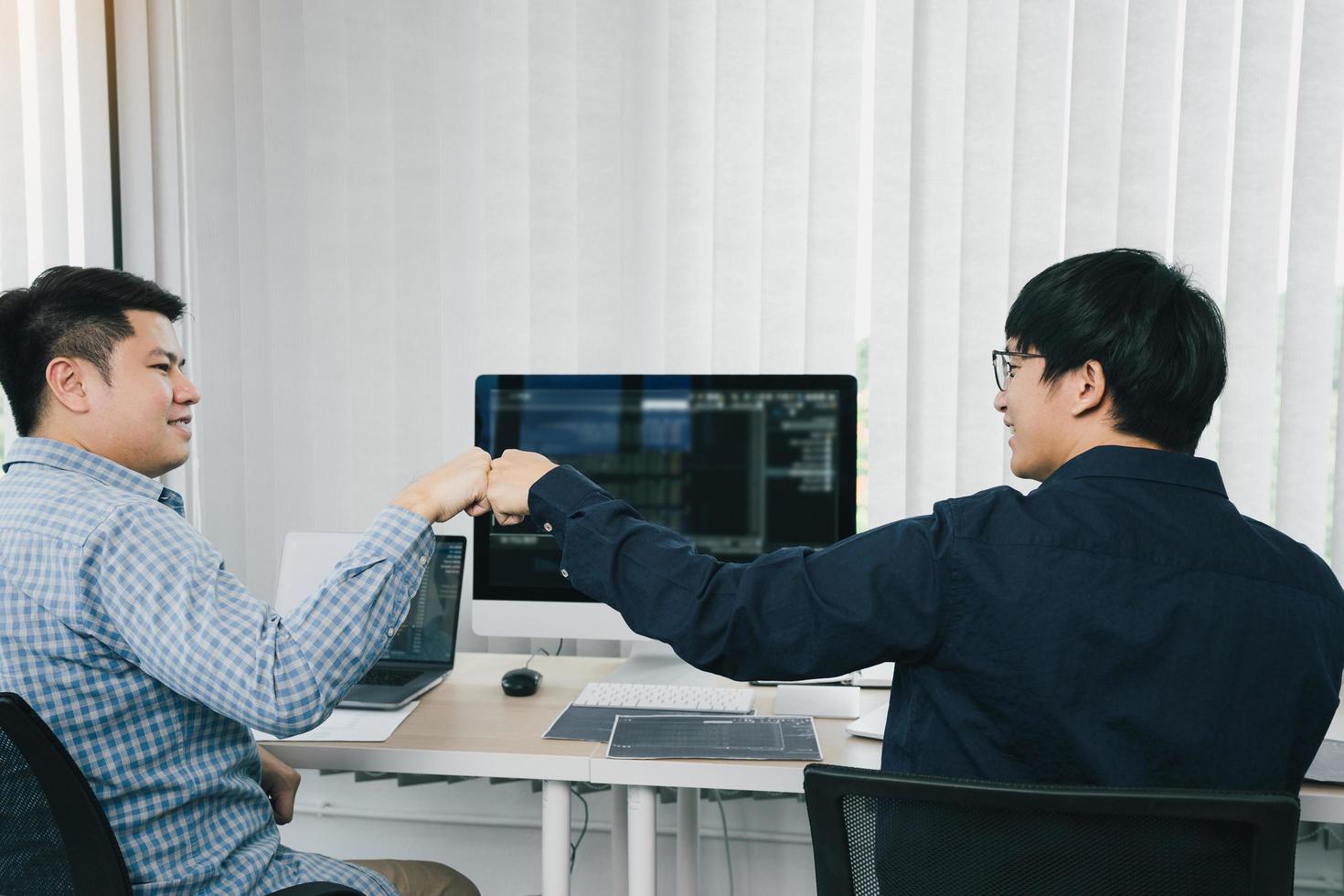Asian employee software developers celebrate success project by fist bump in office room. photo