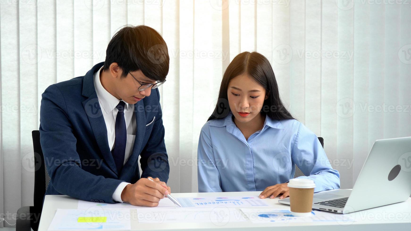 Asian male manager teaches the staff about bookkeeping at their desks. photo