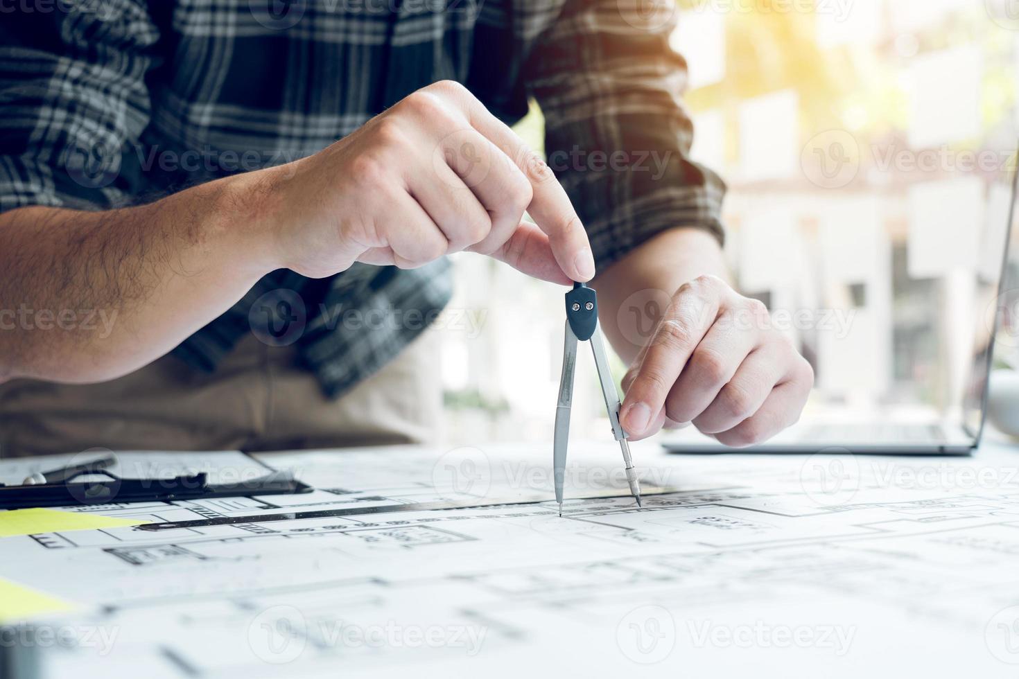 Interior designer or architect reviewing blueprints and holding pencil drawing on desk at home office. photo
