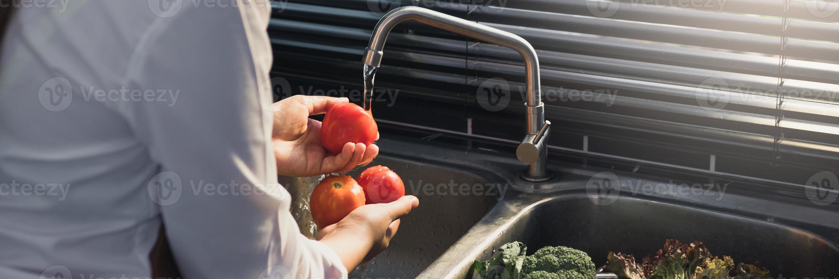 Asian hands woman washing vegetables tomato and preparation healthy food in kitchen. photo